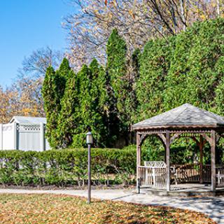 A peaceful park scene featuring a wooden gazebo surrounded by autumn foliage.