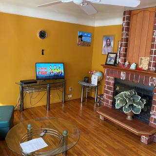 A cozy living room with a television, brick fireplace, and wooden flooring.