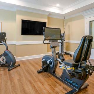 A home gym with stationary bikes and a large TV on the wall.