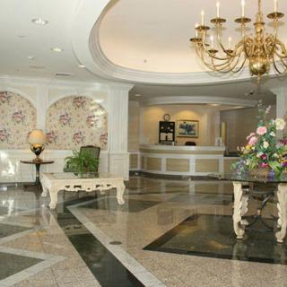 An elegant hotel lobby featuring a chandelier, marble flooring, and a welcoming reception area.