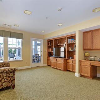 A cozy living room with built-in shelving and cabinetry, featuring comfortable seating and large windows.