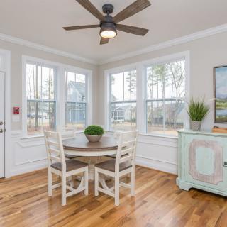 A bright dining room with a round table, chairs, and large windows allowing natural light in.