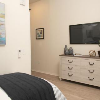 A modern bedroom with a dresser and wall-mounted TV.