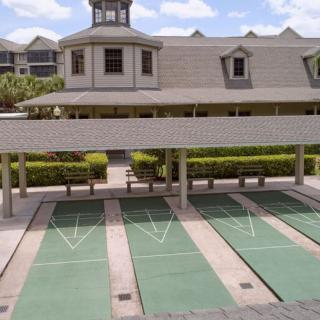 An outdoor shuffleboard court next to a building under a clear sky.