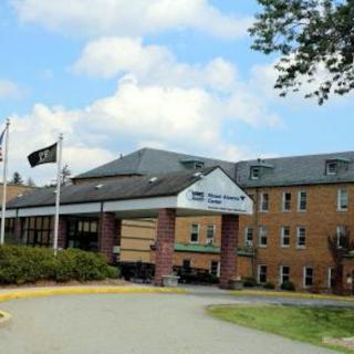 A hospital building with flags and a main entrance under a partly cloudy sky.