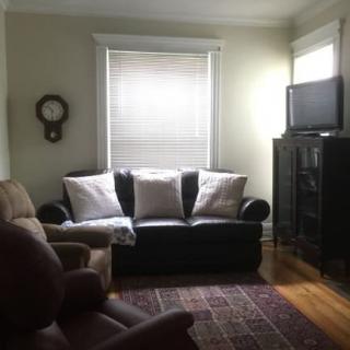 A cozy living room with a sofa, armchair, and television.