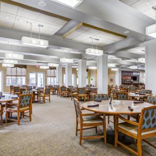 A spacious dining area with neatly arranged tables and chairs, featuring elegant lighting.