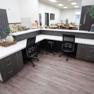 A modern office workspace featuring a corner desk setup with ergonomic chairs and a contemporary design.