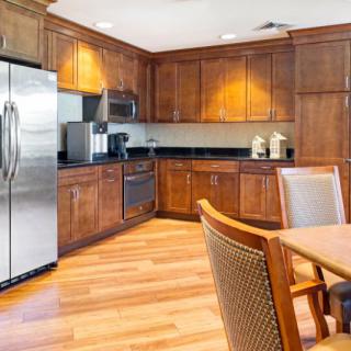 A modern kitchen with wooden cabinetry, stainless steel appliances, and a dining area.