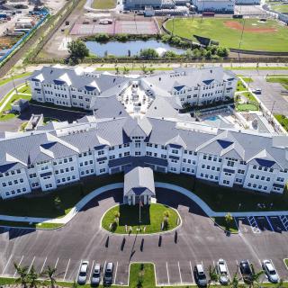 Aerial view of a large building complex with surrounding parking lots and landscaped areas.