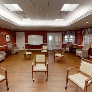 An empty meeting room with chairs arranged in a circle, featuring a whiteboard and wooden flooring.