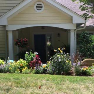A charming house with a neatly landscaped garden and colorful flowers in front of the porch.