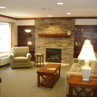 A cozy living room featuring comfortable seating, a central fireplace, and warm lighting.