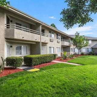 A modern apartment complex with neatly manicured lawns and lush greenery.