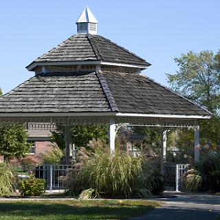 A charming wooden gazebo surrounded by lush greenery in a garden setting.