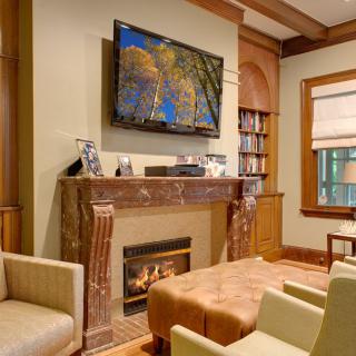 A cozy living room featuring a fireplace, television, and a bookshelf.