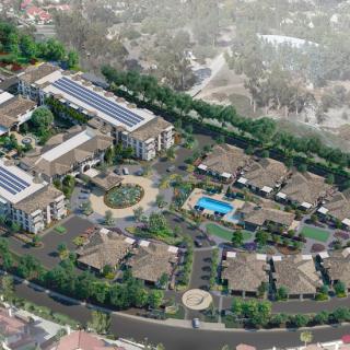 Aerial view of a residential housing complex featuring solar panels, a swimming pool, and landscaped areas.