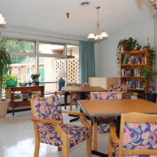 A bright dining area with floral-patterned chairs, a wooden table, and large windows letting in natural light.
