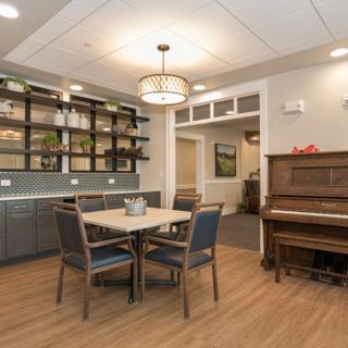 A cozy dining area featuring a table with chairs, a piano, and elegant decor.