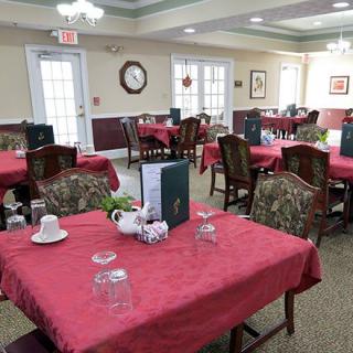 A neatly arranged dining room with tables covered in red tablecloths and set for guests.