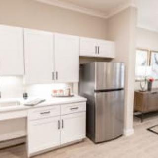 A modern kitchen with white cabinets and stainless steel fridge.