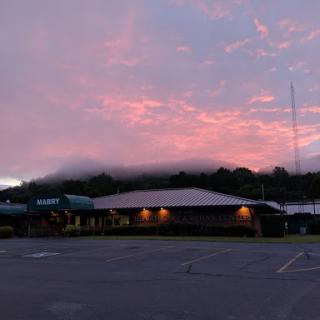 A serene sunset casts a warm glow over the building and surrounding landscape.