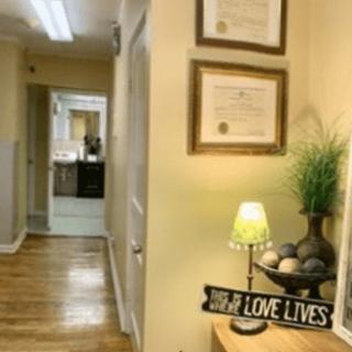 A cozy hallway decorated with certificates, a small lamp, and a sign reading 'LOVE LIVES HERE'.