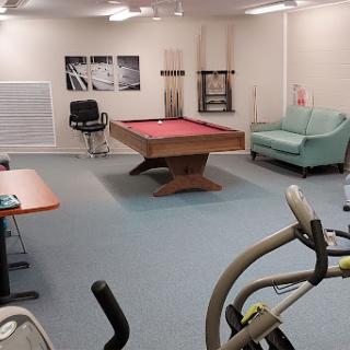 A recreational room featuring a pool table, exercise equipment, and a cozy seating area.