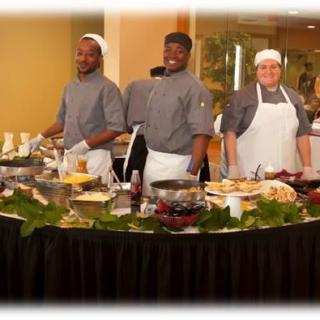 A team of chefs preparing dishes at a buffet station during a culinary event.