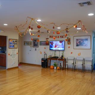 A decorated room with a television, artwork on the walls, and chairs arranged neatly.