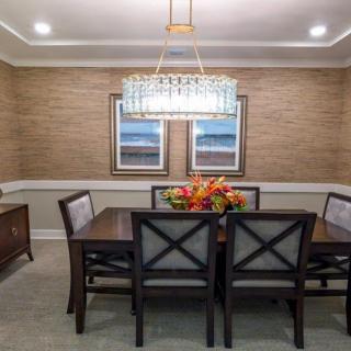 A well-decorated dining room featuring a stylish chandelier, a rectangular table with chairs, and wall artwork.