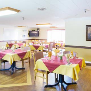A cozy dining area featuring neatly arranged tables with yellow and red tablecloths, providing a warm atmosphere.