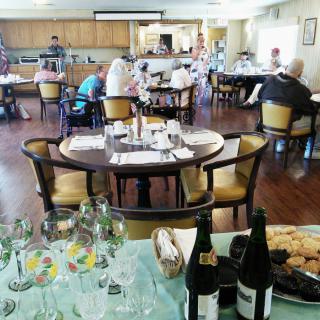 A cozy dining area with several tables set for guests, featuring wine bottles and glasses in the foreground.