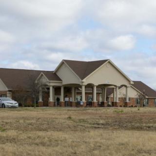 A large suburban house with a spacious front lawn under a cloudy sky.