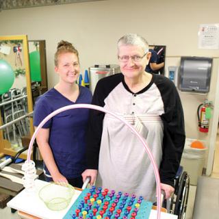 A therapist and a patient engage in a rehabilitation activity together, focusing on wellness and support.