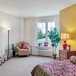 A cozy bedroom with a large window, colorful decor, and comfortable furniture.