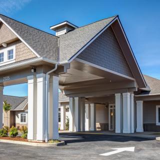 A modern building entrance featuring large columns and a pitched roof.