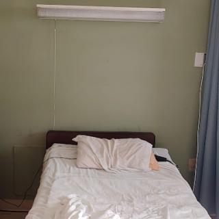 A simple, neatly made bed with light bedding in a minimalist room.