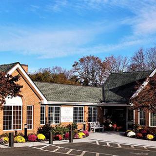 A brick building with a sloped roof surrounded by trees and under a clear blue sky.