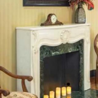 A decorated fireplace with a clock, vase, and candles on the mantel.