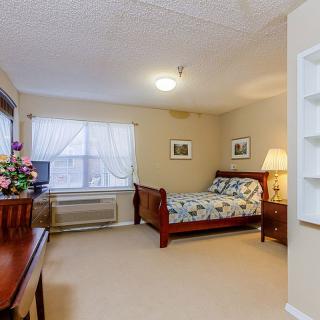 A cozy bedroom with a wooden bed, floral bedding, and natural lighting.