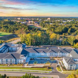 Aerial view of a large building complex surrounded by trees at sunset.
