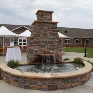 A stone fountain in an outdoor setting, surrounded by a round basin.