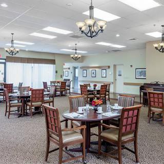 Spacious dining area with wooden tables and chairs, adorned with chandeliers.