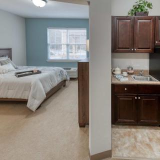 A cozy studio apartment with a bedroom area and a kitchenette.