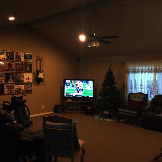 A cozy living room with a TV, guitar on the wall, and holiday decorations.