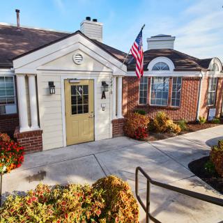 A quaint building with a golden door and an American flag, surrounded by a well-maintained garden path.