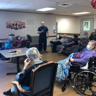 A group of senior citizens gathered in a nursing home for a meeting.