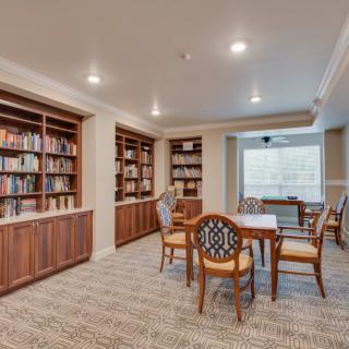 Cozy library space with bookshelves, a reading table, and chairs.