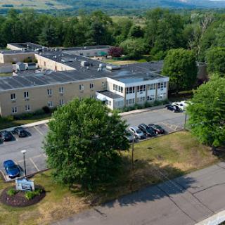 Aerial view of a building surrounded by trees and a parking lot.